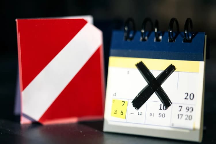 Um sinal de 'atenção' ao lado de um calendário com um X